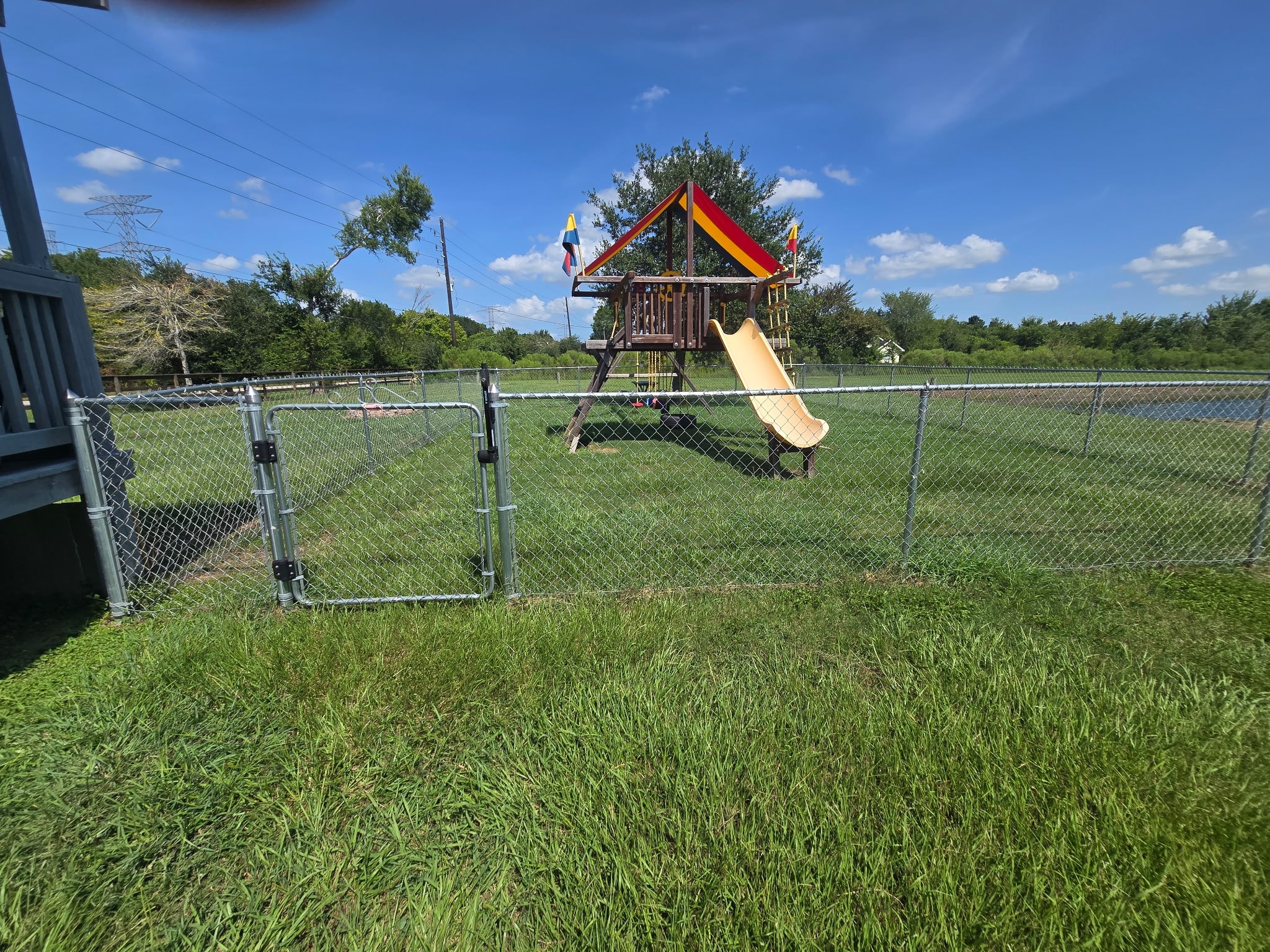 Fenced playground with wooden play structure and slide for kids at The Bend RV Park